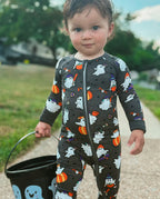 Toddler wearing Ghostie Sports Club Bamboo Zippy standing outdoors in a dark Halloween ghost print zippy