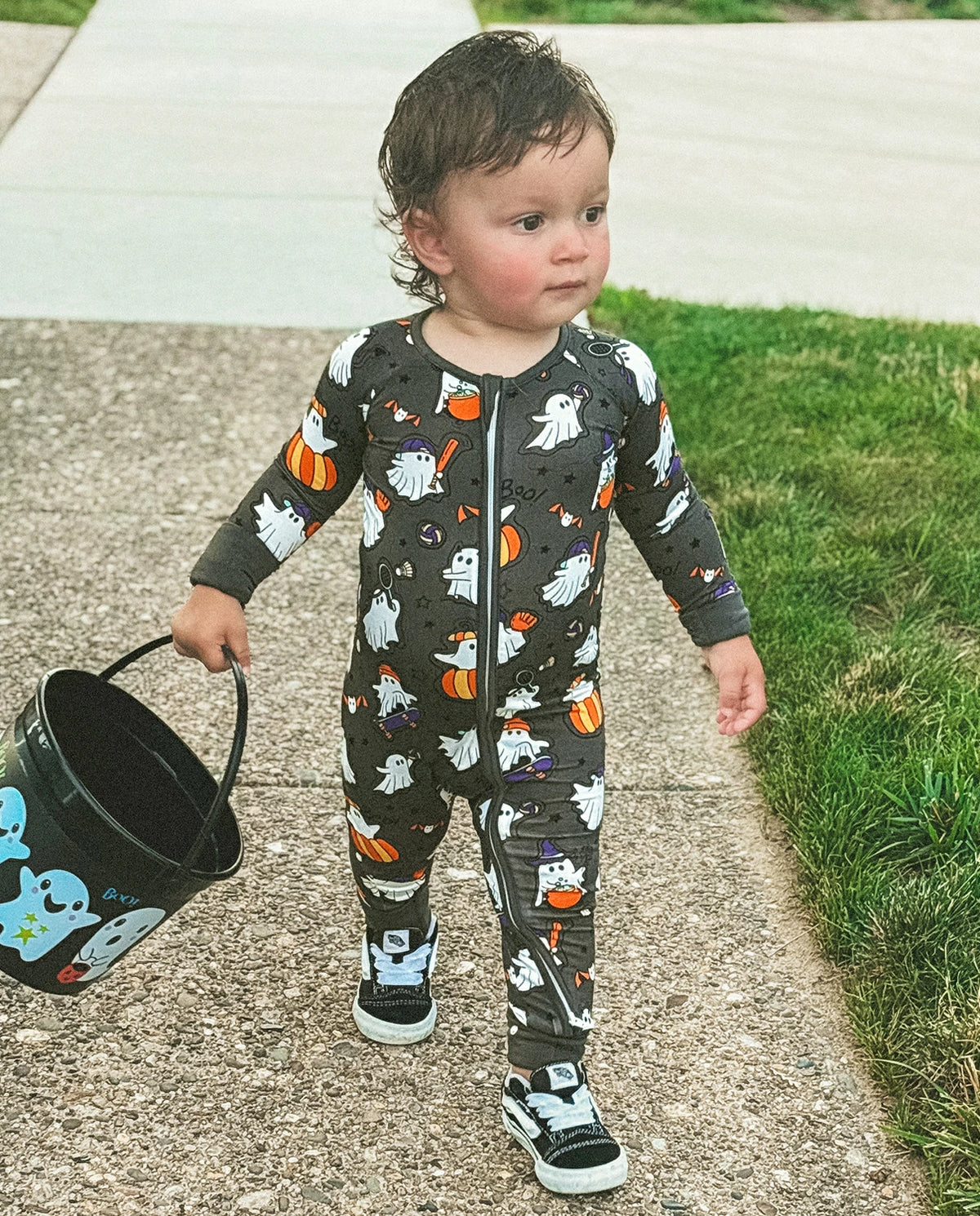 Toddler wearing Ghostie Sports Club Bamboo Zippy standing outdoors with Halloween bucket and sneakers