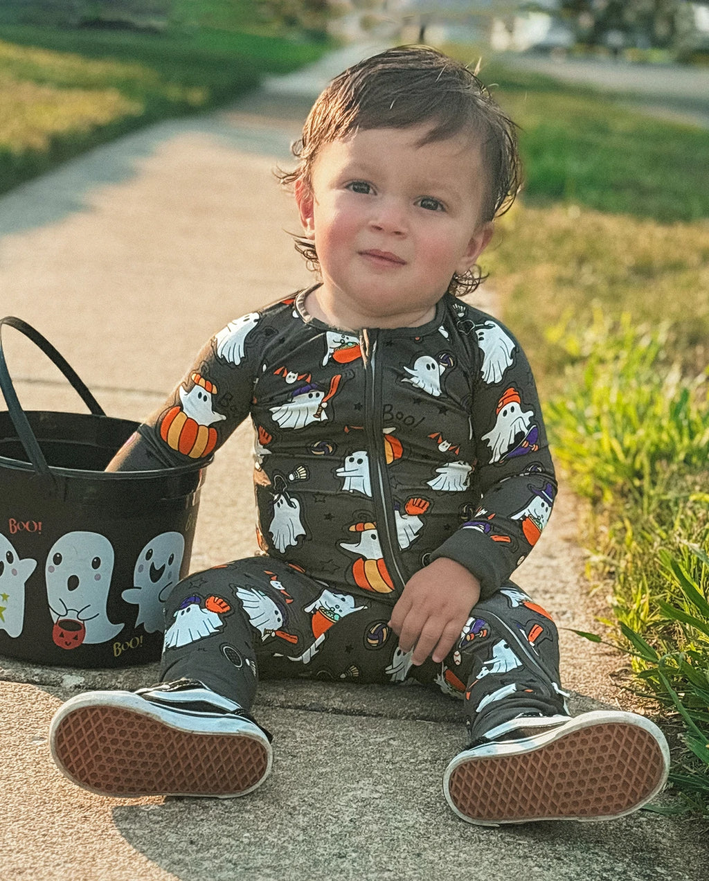 Toddler sitting outdoors in Ghostie Sports Club Bamboo Zippy next to a Halloween ghost bucket