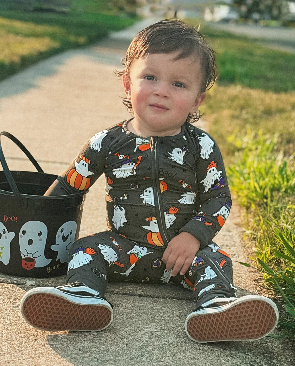 Toddler sitting outdoors in Ghostie Sports Club Bamboo Zippy next to a Halloween ghost bucket