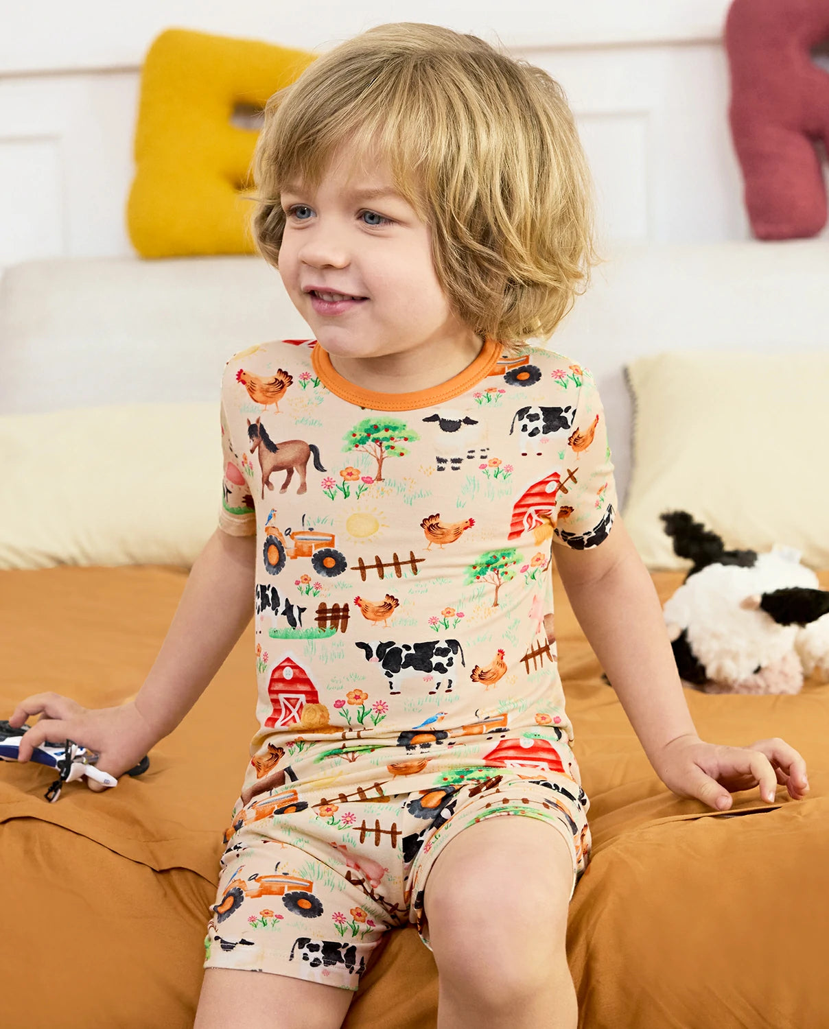 Happy Farmyard Short Two-Piece Pajama Set - child wearing the short pajamas while seated, front view