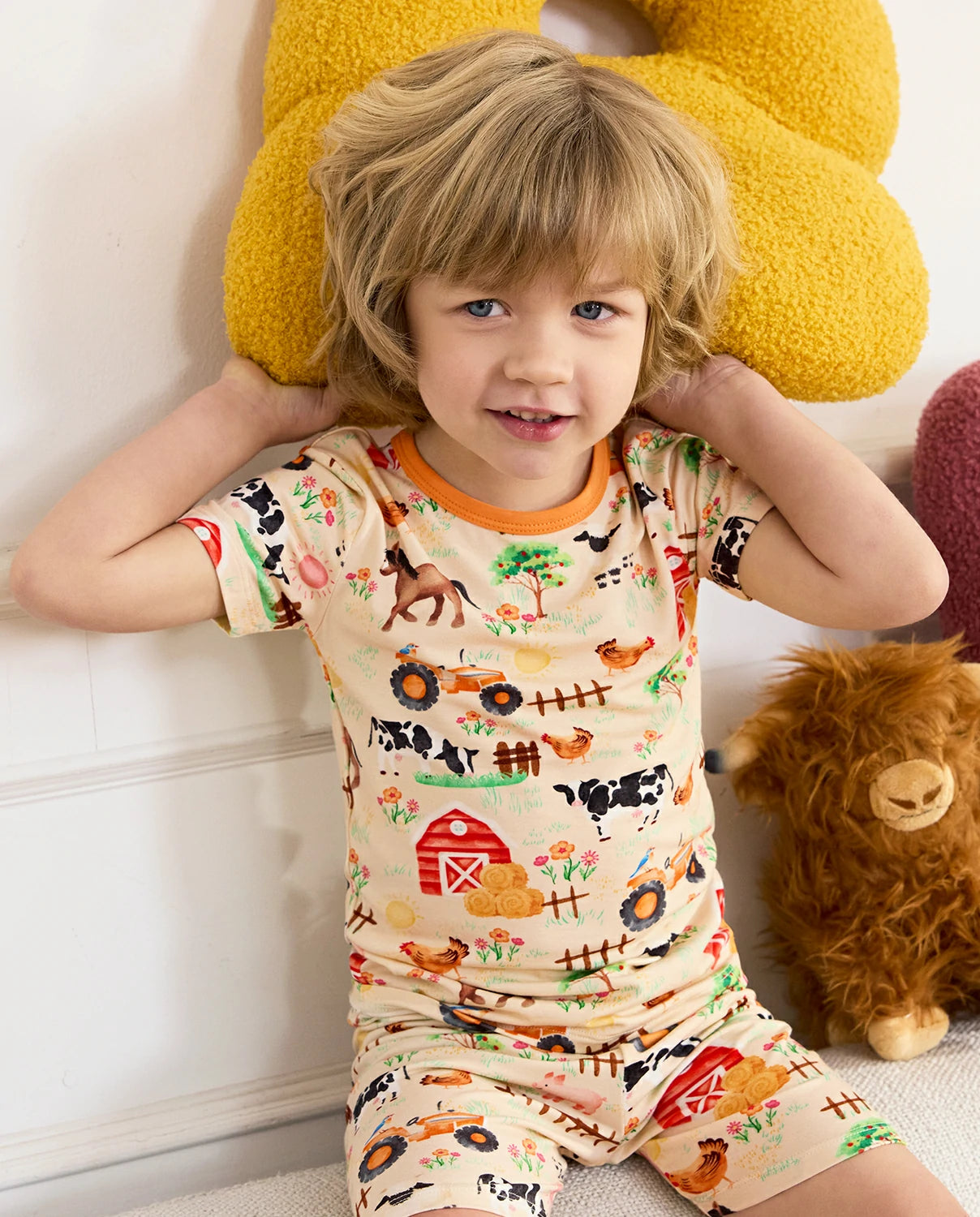 Happy Farmyard Short Two-Piece Pajama Set - child wearing the short pajamas with stuffed animals on both shoulders