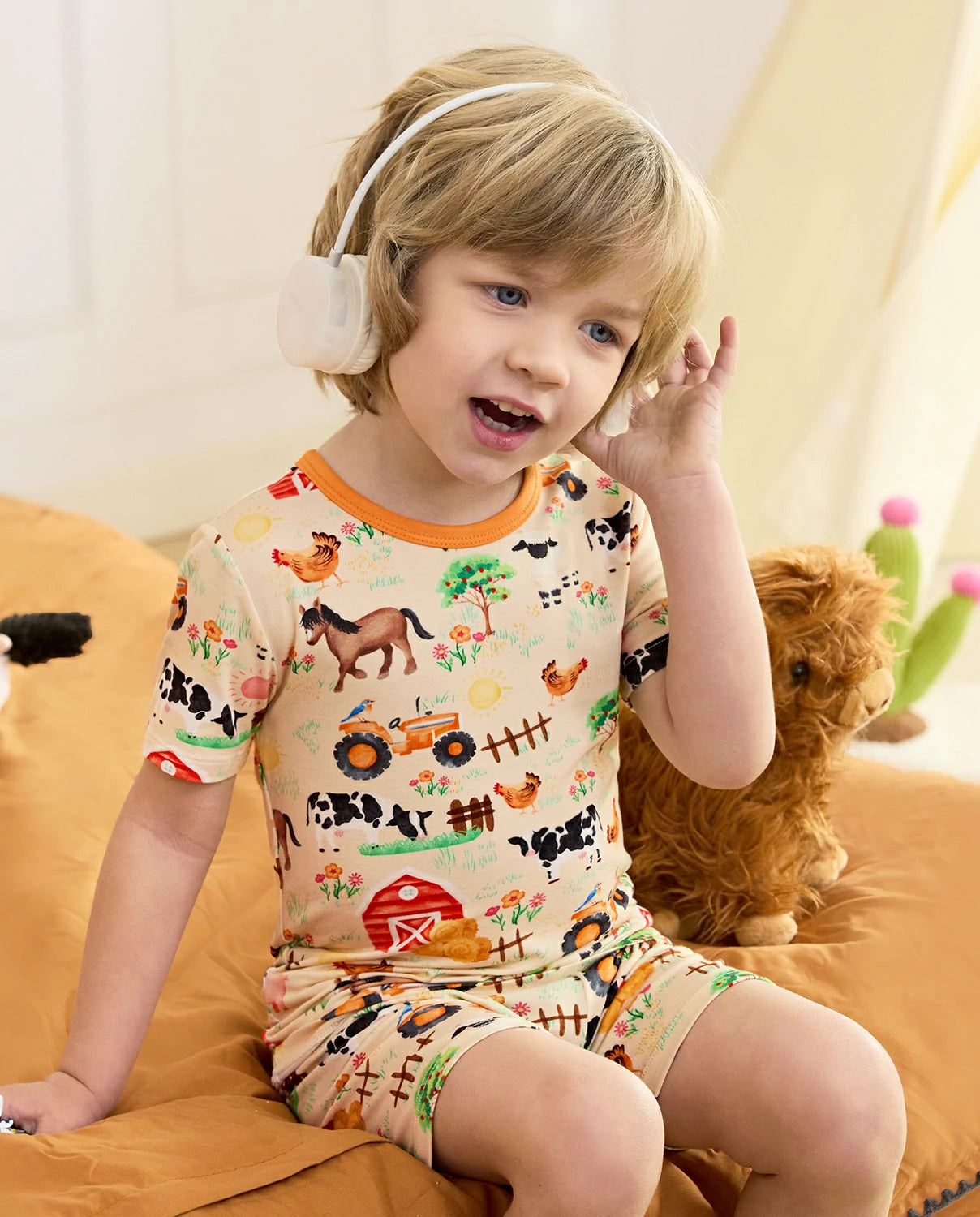 Happy Farmyard Short Two-Piece Pajama Set - child wearing the short pajamas while seated with headphones