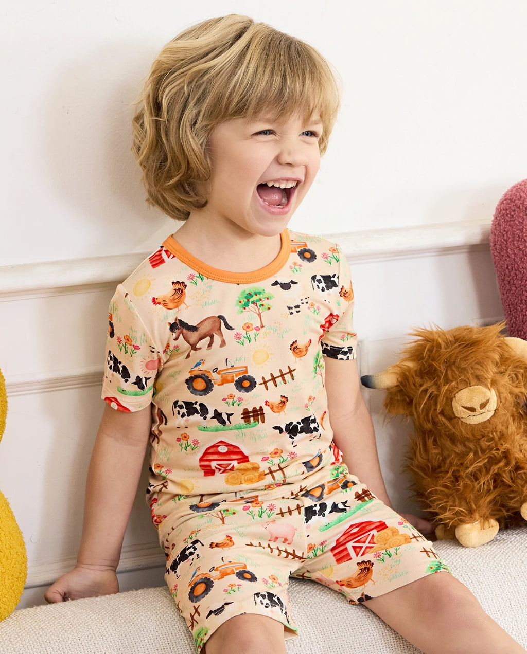 Happy Farmyard Short Two-Piece Pajama Set - child wearing the short pajamas while seated and laughing