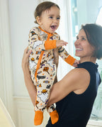 Baby in Happy Hallowboo Bamboo Zippy being held by caregiver in bright indoor setting