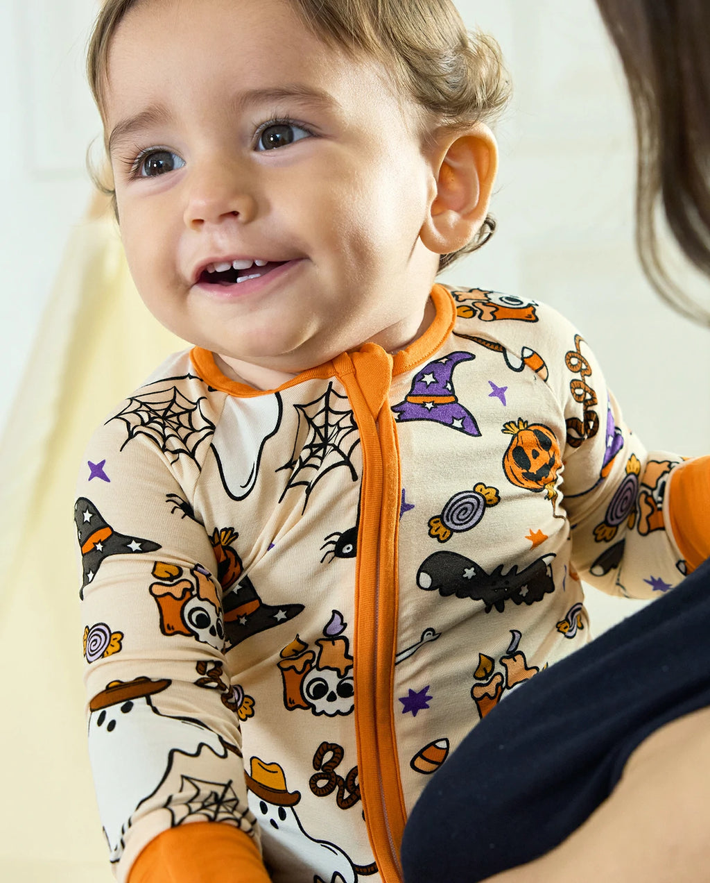 Smiling baby in Happy Hallowboo Bamboo Zippy with Halloween ghost and pumpkin print