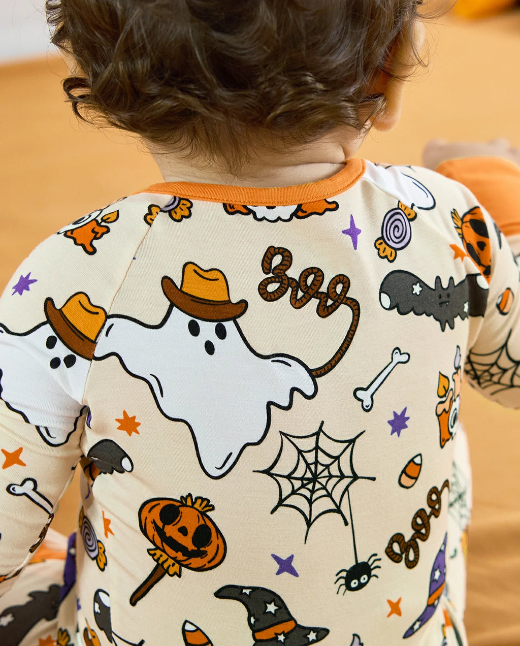 Baby standing in Happy Hallowboo Bamboo Zippy with back Halloween print visible