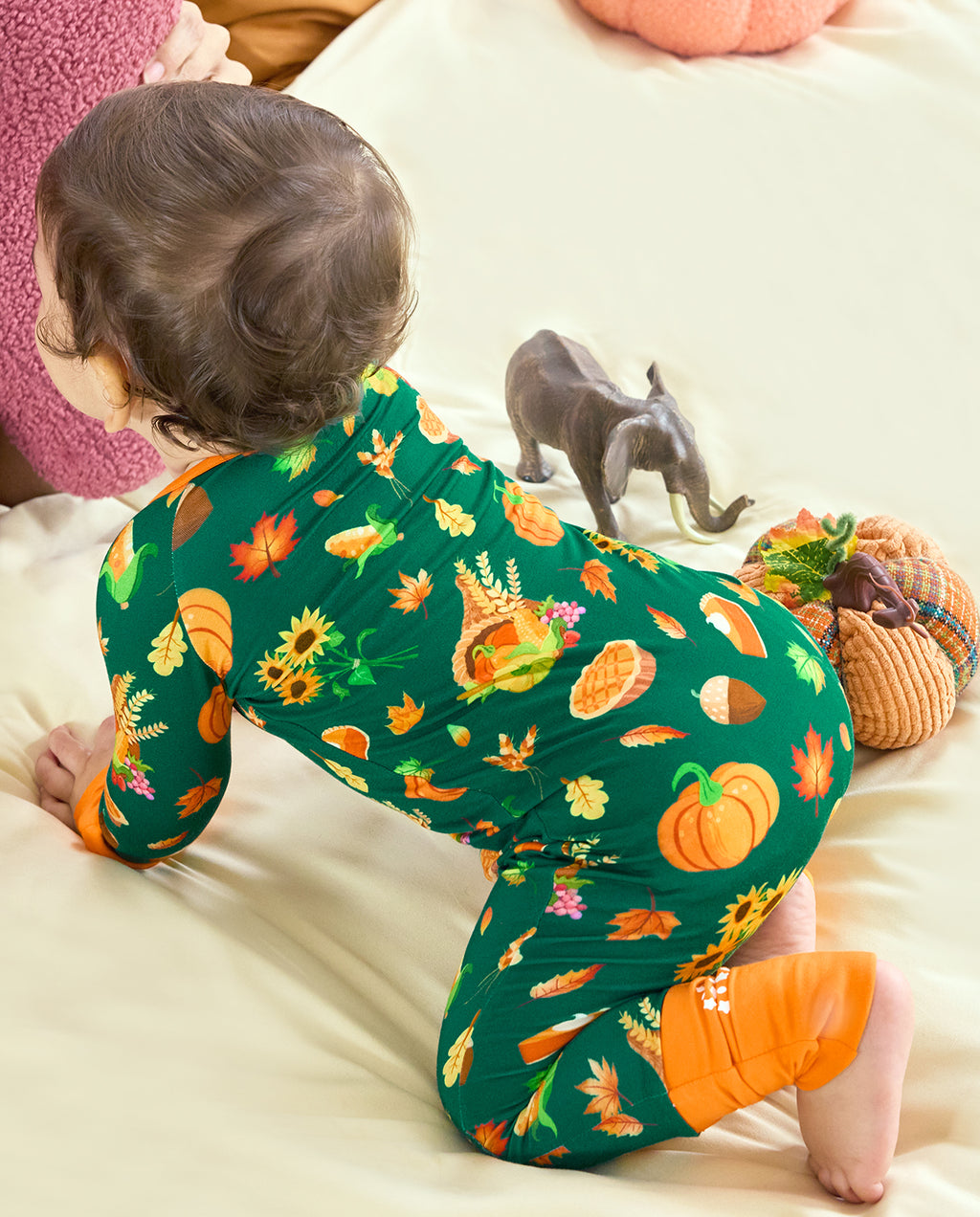 Back view of a baby crawling in Harvest Feast Bamboo Zippy with pumpkins and autumn leaves.