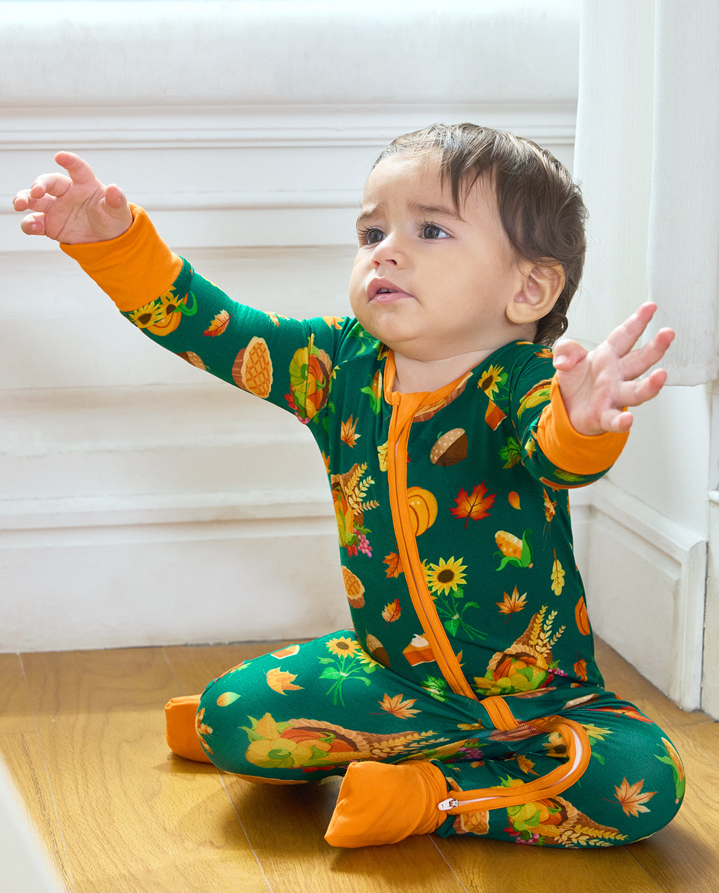 Baby seated in Harvest Feast Bamboo Zippy with orange trim and harvest print.