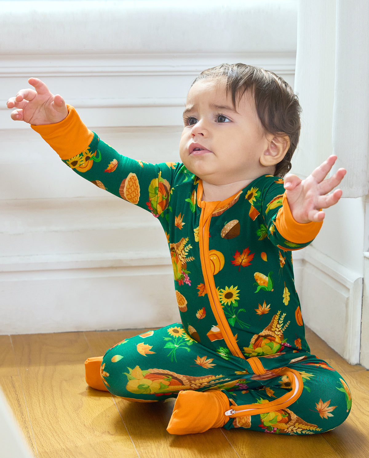 Baby seated in Harvest Feast Bamboo Zippy with orange trim and harvest print.
