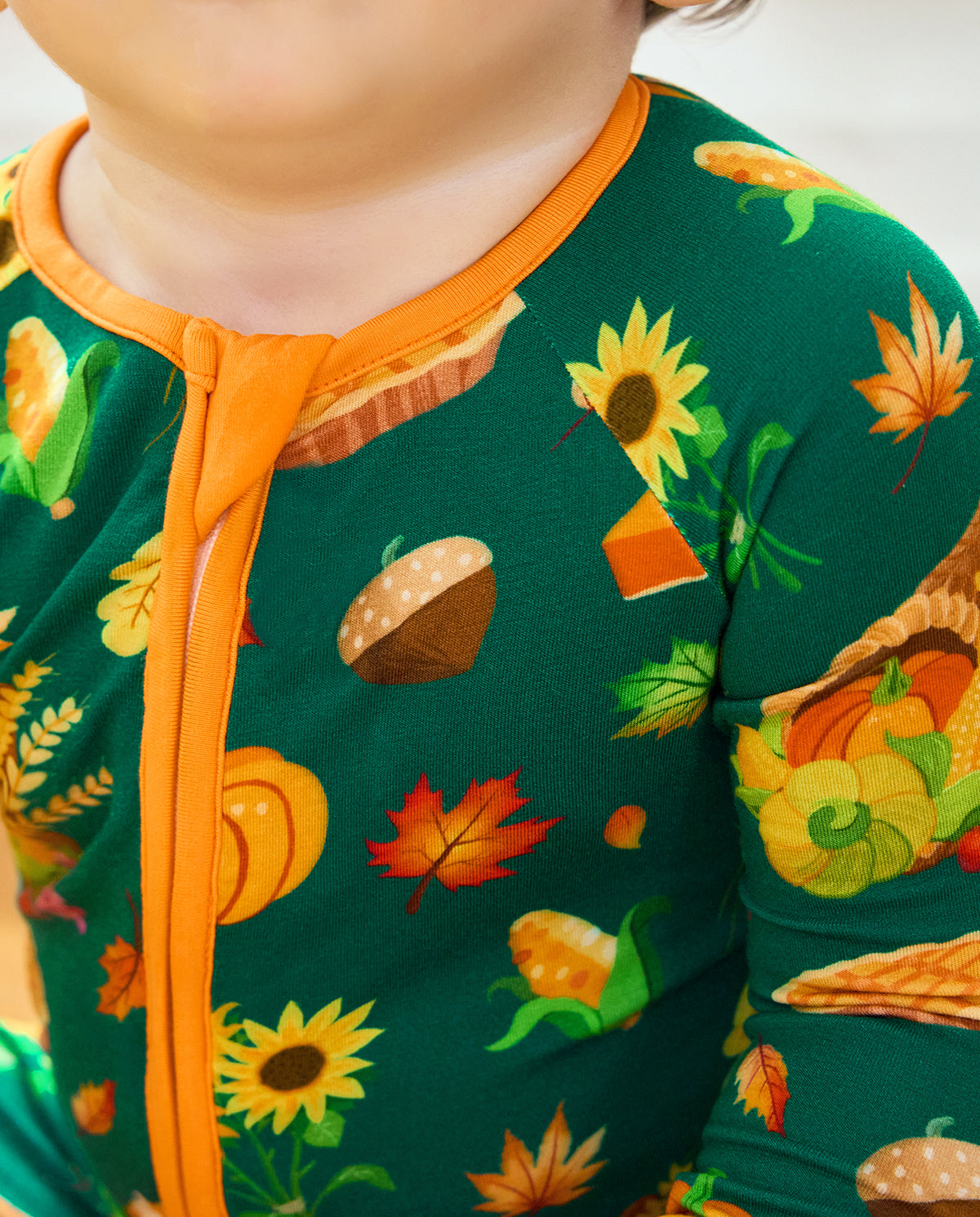 Close-up of Harvest Feast Bamboo Zippy showing orange zipper, pumpkin and sunflower print.
