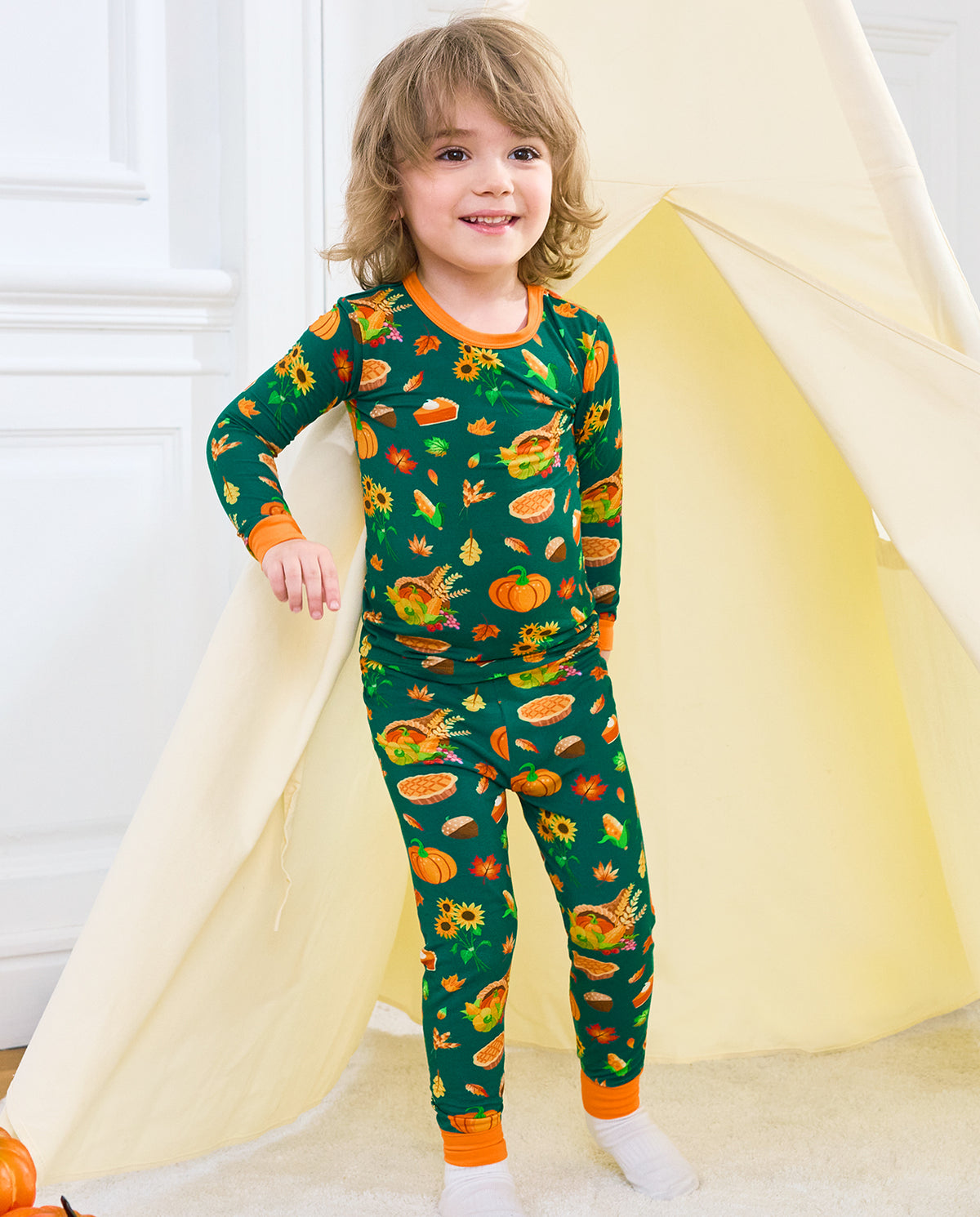 Child wearing Harvest Feast long two-piece pajamas in front of a play tent.