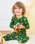 Child seated in Harvest Feast long two-piece pajamas with orange trim while holding a plush harvest toy.