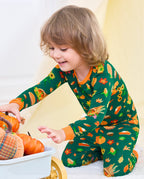 Child wearing Harvest Feast long two-piece pajamas while reaching toward a harvest display.