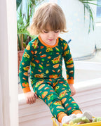 Child seated by a window in Harvest Feast long two-piece pajamas with orange trim.