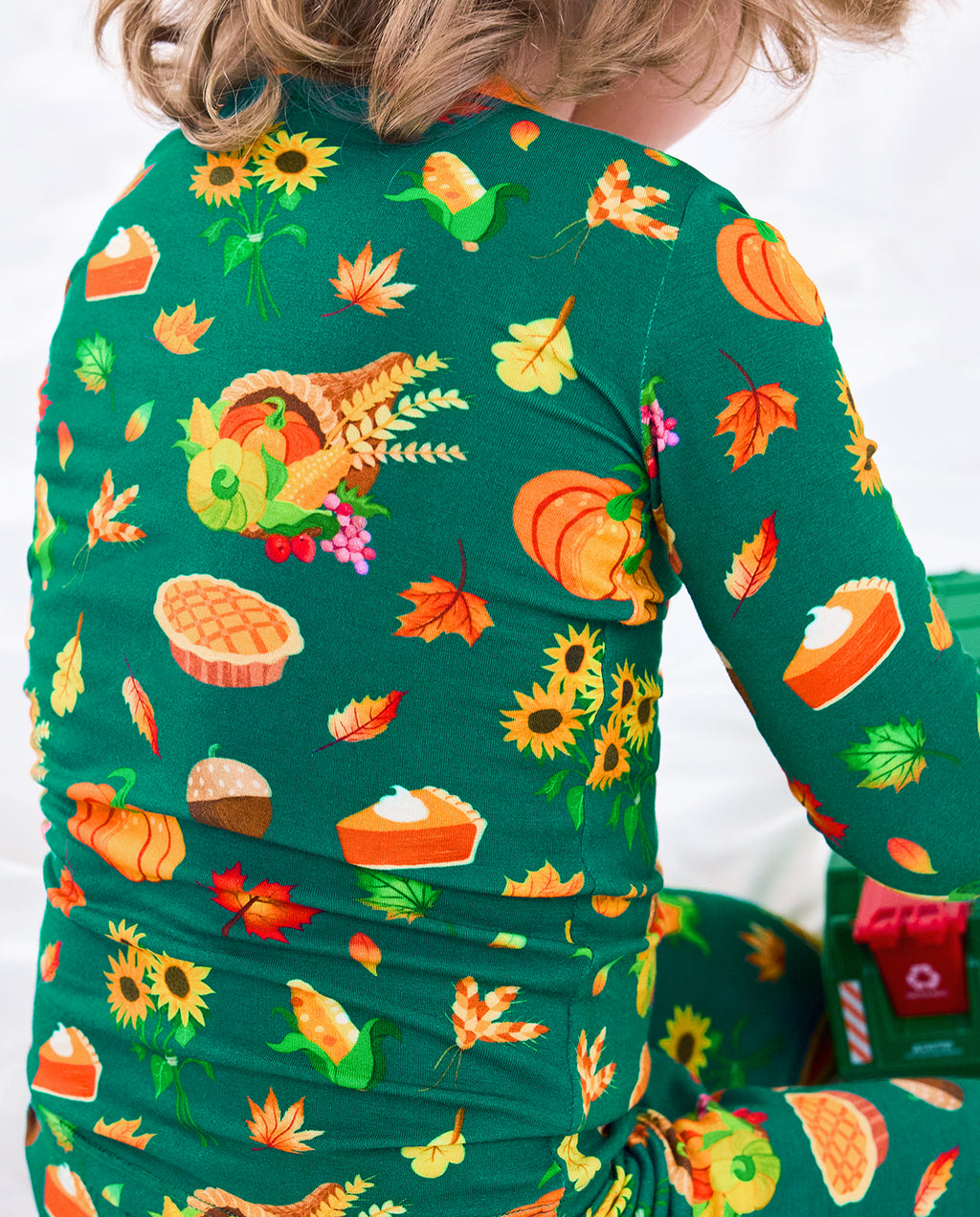 Close-up back view of Harvest Feast long two-piece pajamas with pumpkins, corn, sunflowers, wheat, pies, and autumn leaves.