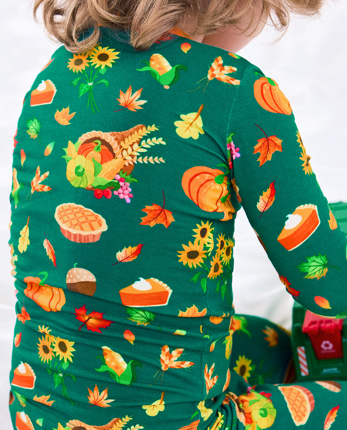 Close-up back view of Harvest Feast long two-piece pajamas with pumpkins, corn, sunflowers, wheat, pies, and autumn leaves.