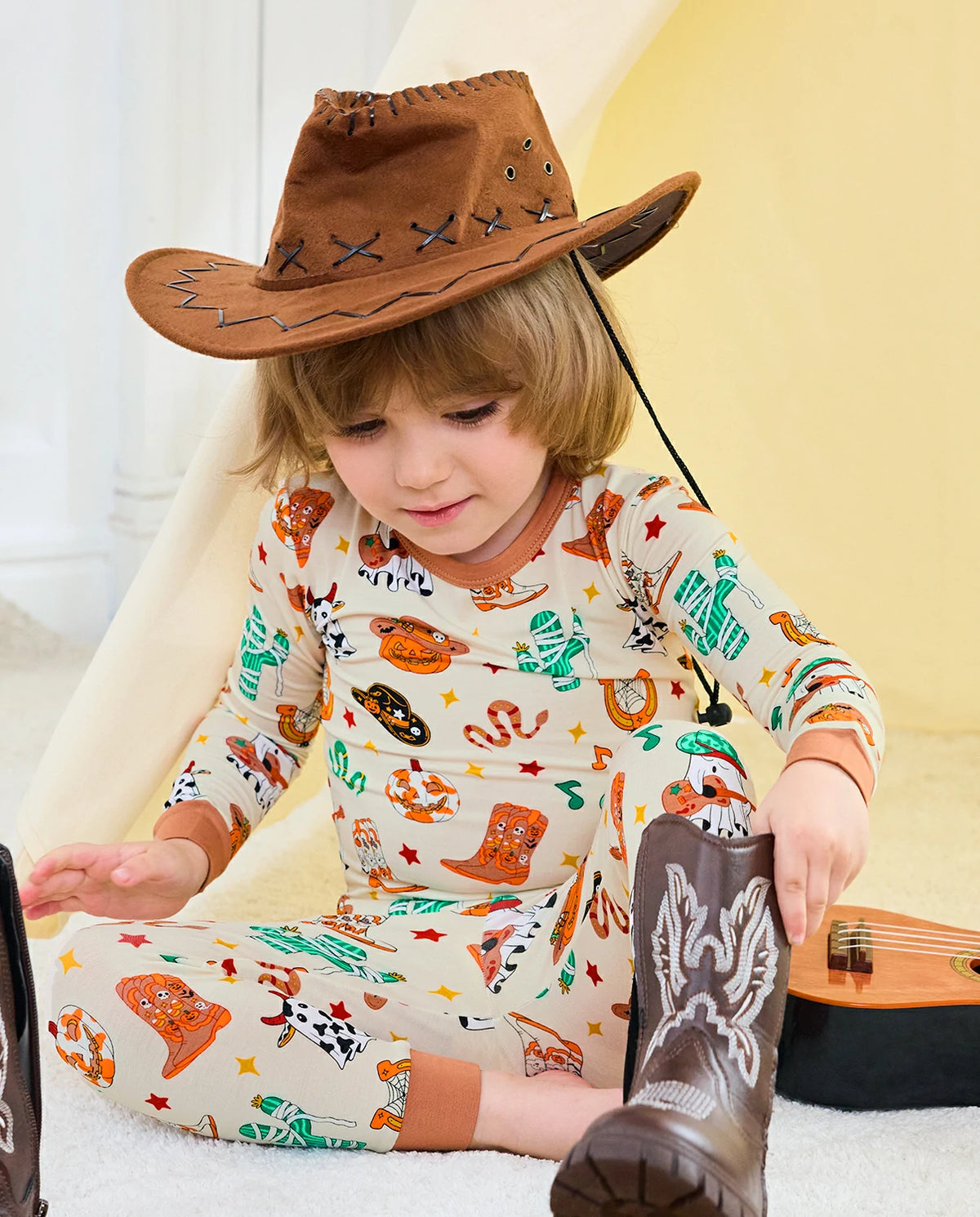 Howdy Halloween Long Two-Piece Pajama Set - child wearing the pajamas with a cowboy hat and boots while seated