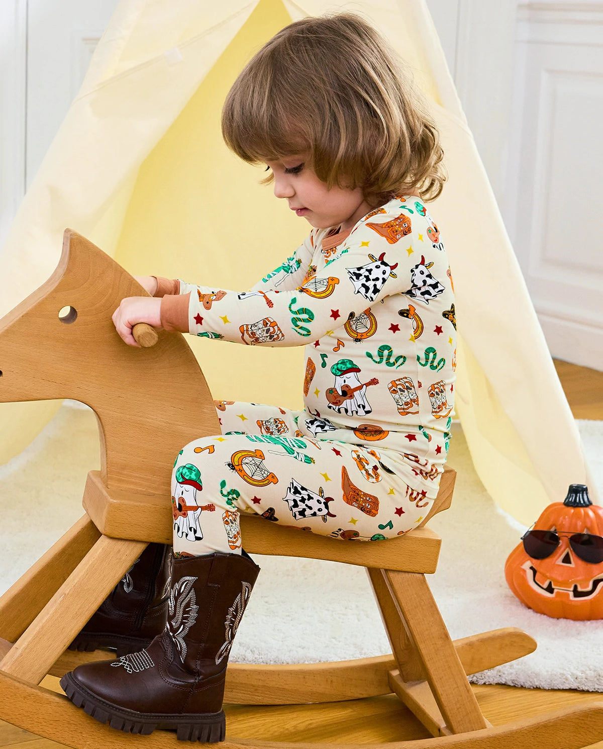 Howdy Halloween Long Two-Piece Pajama Set - child wearing the pajamas on a rocking horse, side view