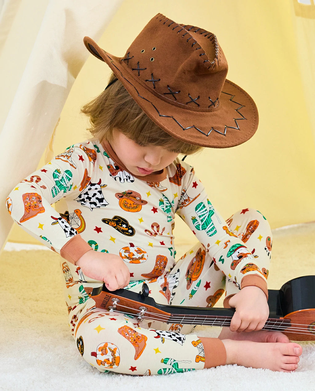 Howdy Halloween Long Two-Piece Pajama Set - child wearing the pajamas while seated with a guitar