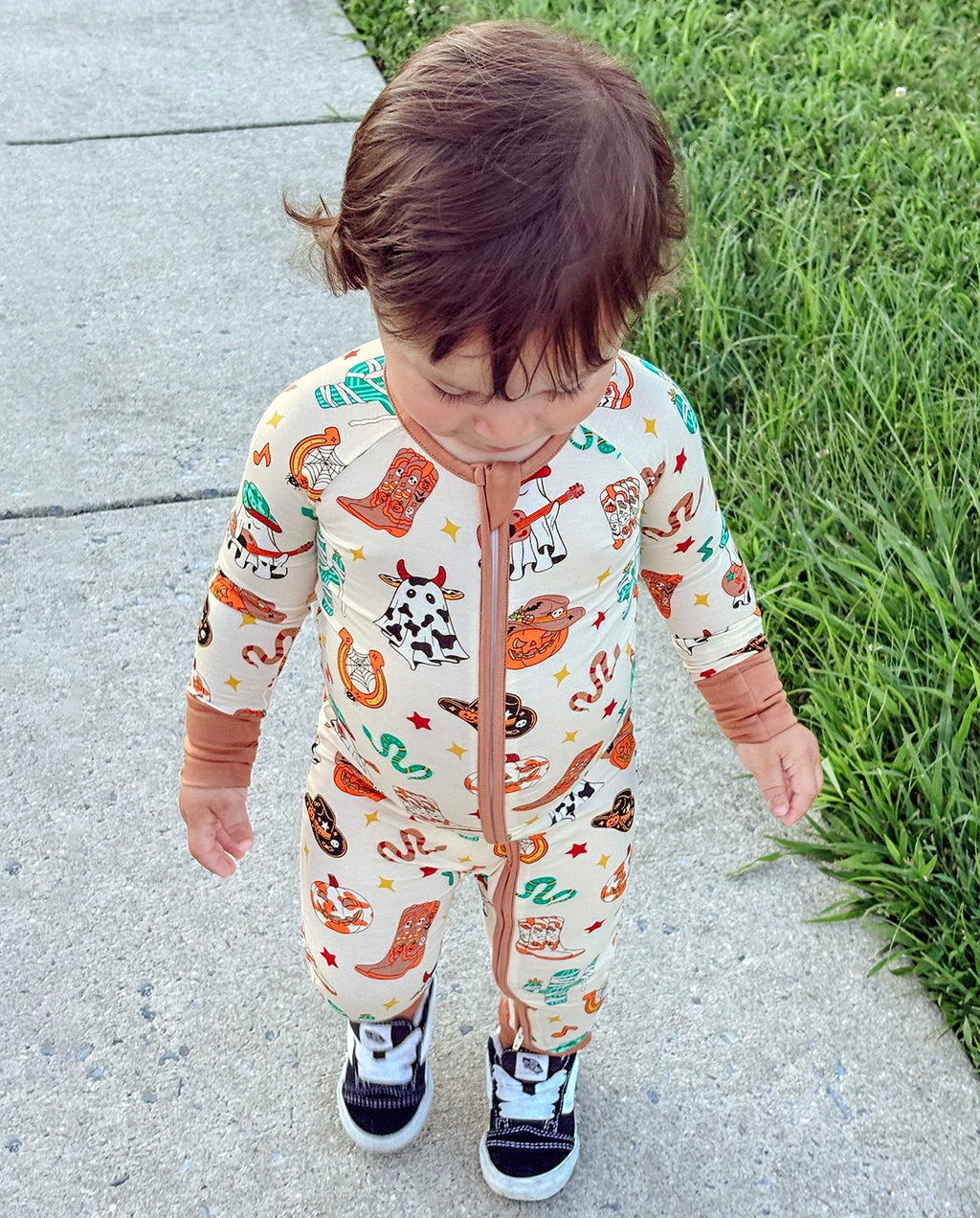 Child wearing Howdy Halloween Bamboo Zippy while walking outdoors on a sidewalk
