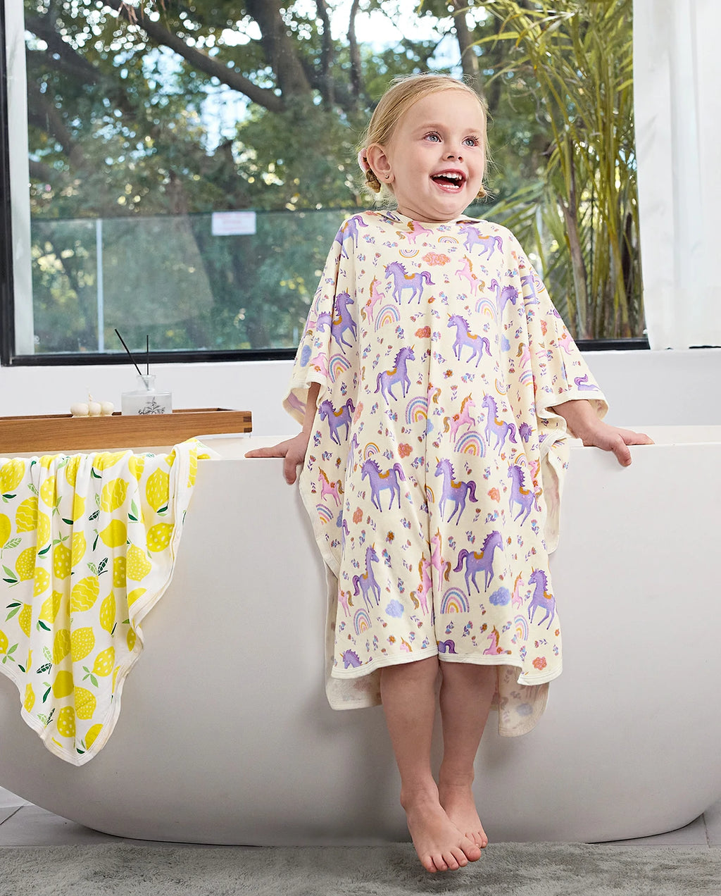 Lavender Unicorn Hooded Toddler Bath Towel - child wearing the unicorn-print hooded towel beside a bathtub