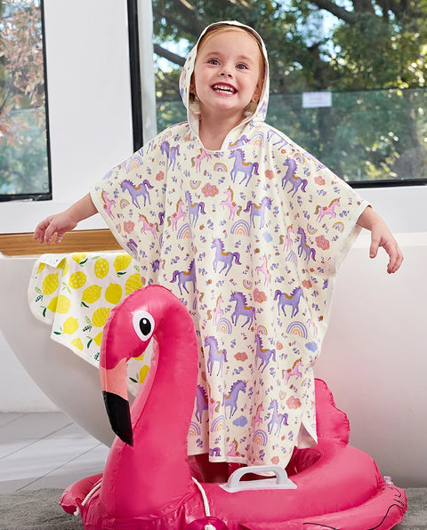 Lavender Unicorn Hooded Toddler Bath Towel - child wearing the hooded towel while seated on a flamingo pool float