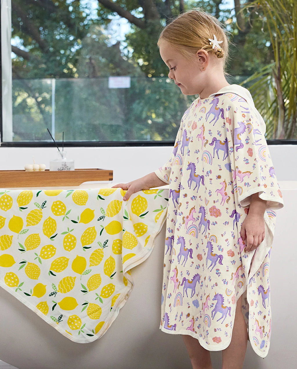 Lavender Unicorn Hooded Toddler Bath Towel - child wearing the hooded towel beside a bathtub, side view