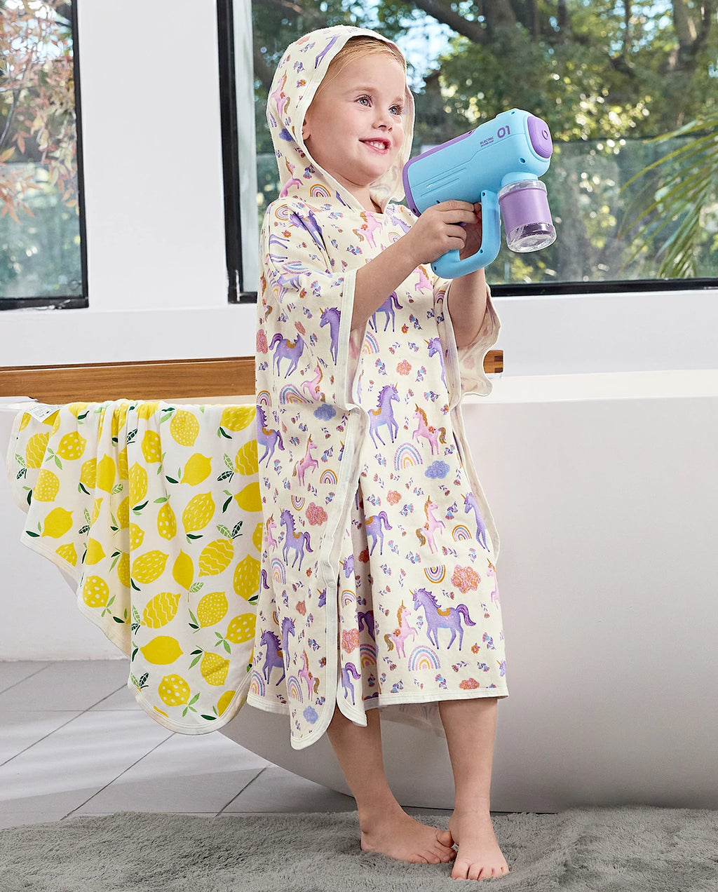 Lavender Unicorn Hooded Toddler Bath Towel - child wearing the hooded towel while holding a water toy