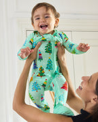 Baby held up wearing the mint-green Merry Trees Bamboo Zippy with colorful Christmas trees