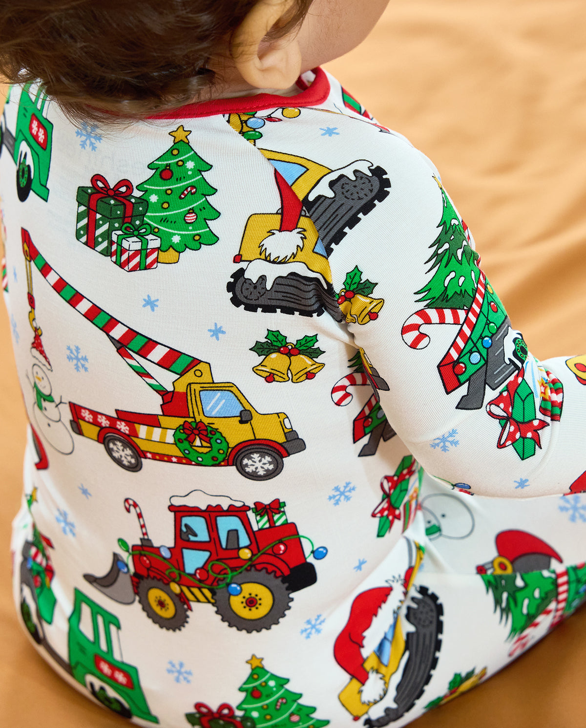 Close-up of Christmas crane trucks, tractors, trees and gifts on the back of the Merry Truckmas Bamboo Zippy.