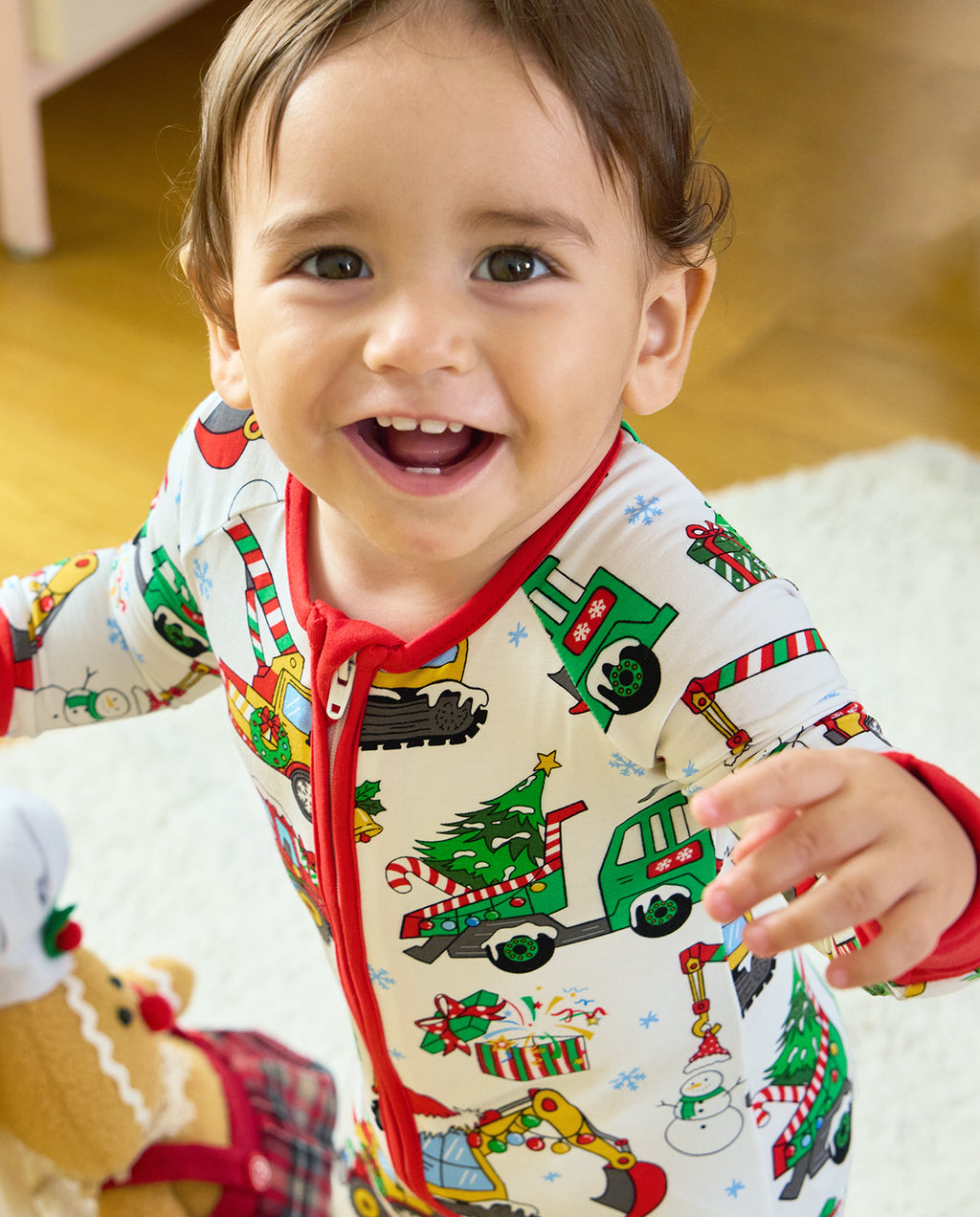 Smiling child wearing the Merry Truckmas Bamboo Zippy with a red zipper and Christmas construction-vehicle print.