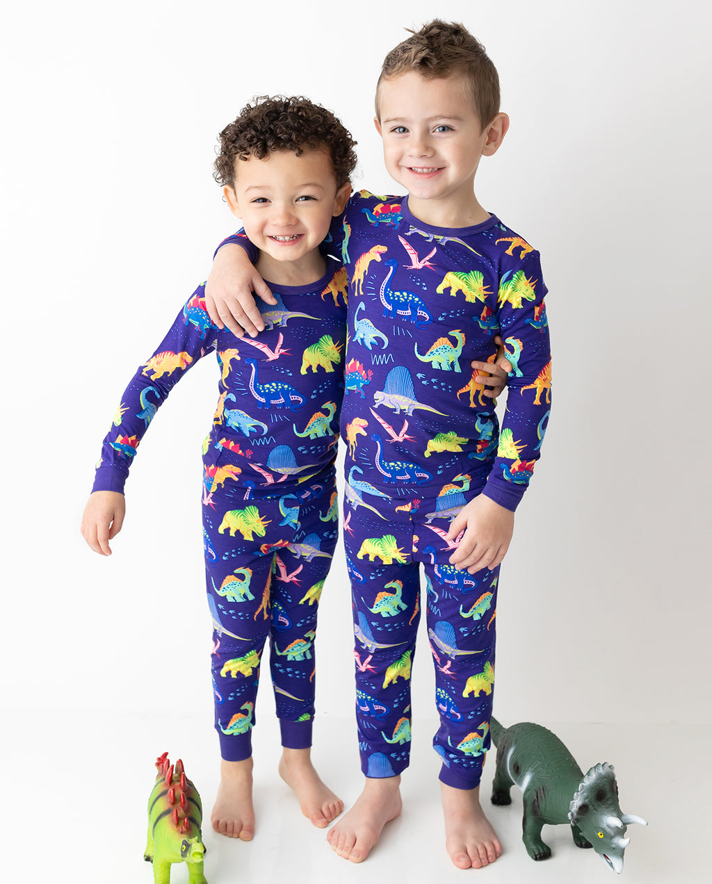 Two children standing in colorful Neo Dino pajamas