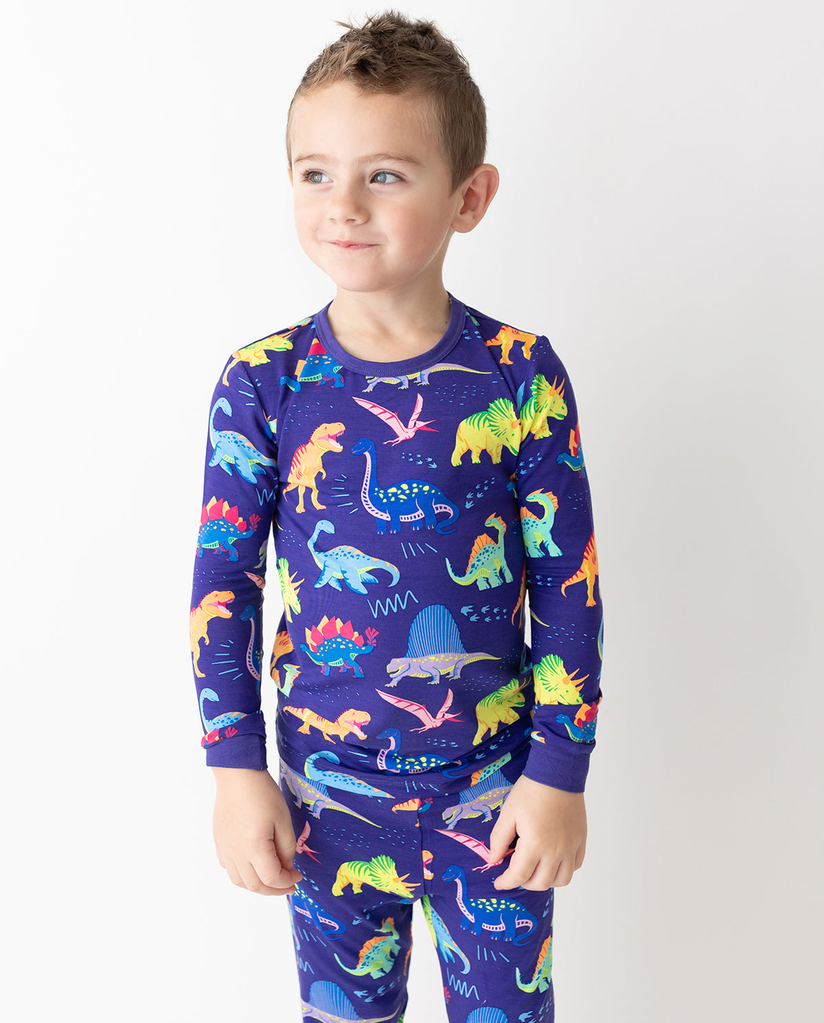 Child wearing Neo Dino pajamas with colorful dinosaurs
