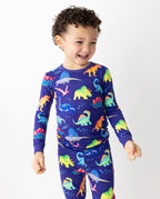 Child smiling in colorful dinosaur-print pajamas