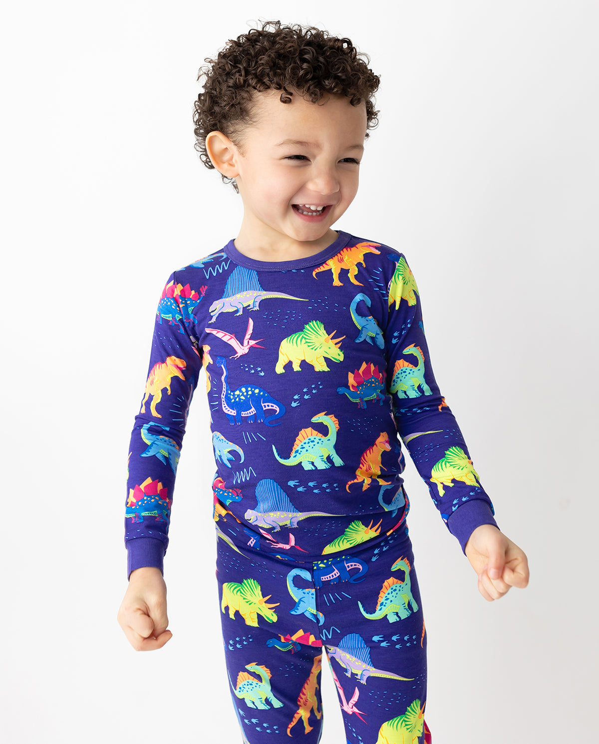 Child smiling in colorful dinosaur-print pajamas