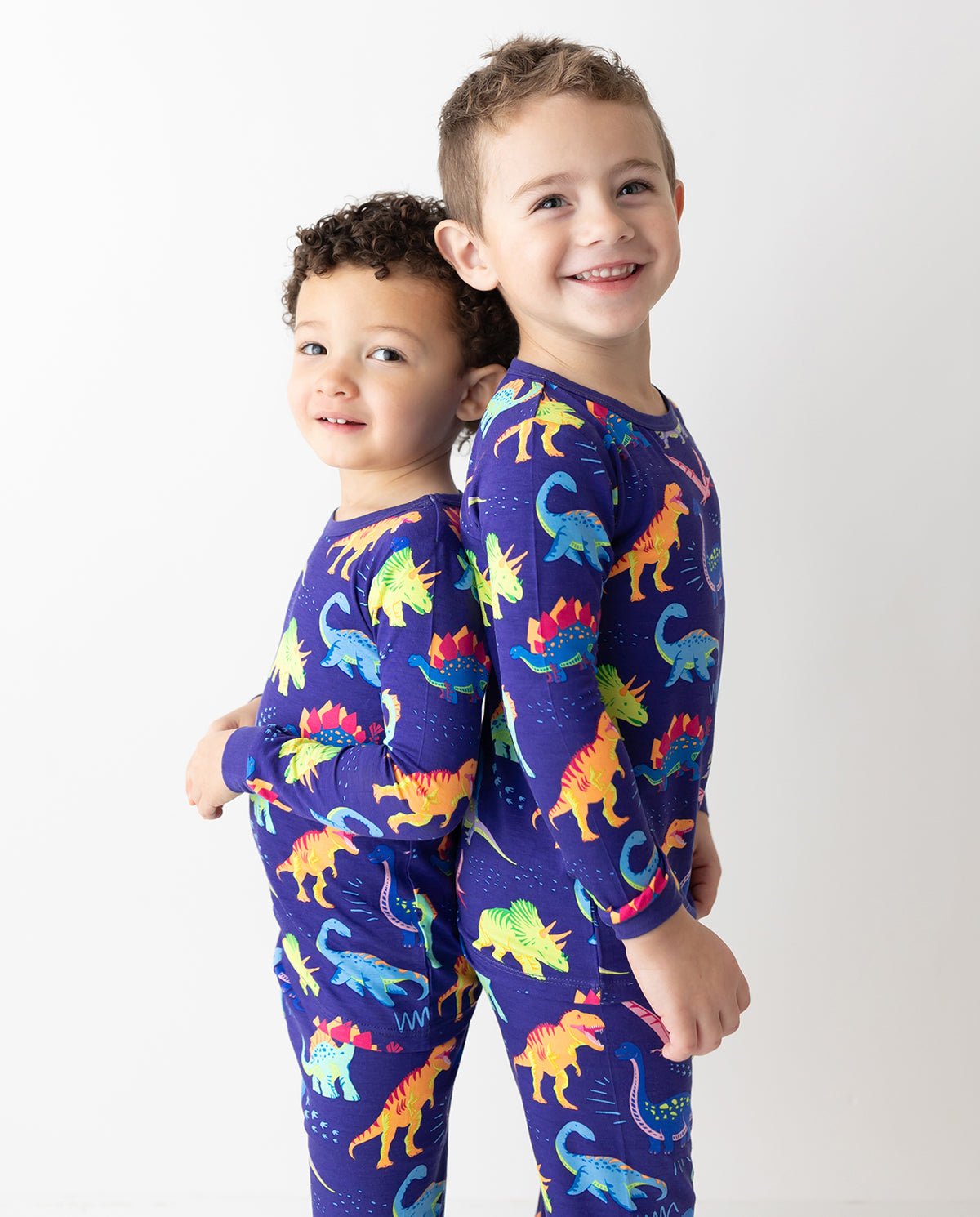Two children standing together in Neo Dino pajamas