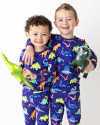 Two children seated with toy dinosaurs in Neo Dino pajamas