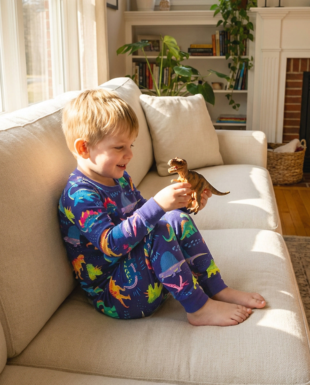 Child seated on a sofa in colorful Neo Dino pajamas