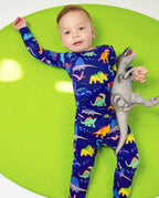 Baby reclining on a green seat in Neo Dino pajamas