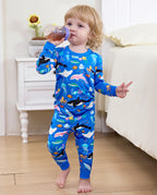 Child wearing blue sea-creature pajamas while holding a cup