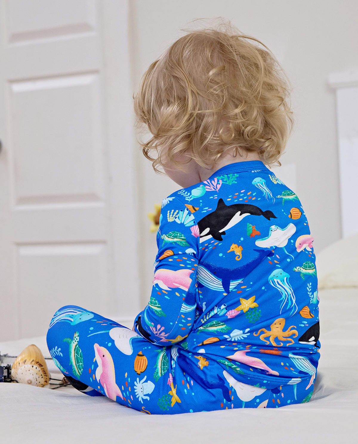 Back view of a child seated in blue Ocean Friends pajamas