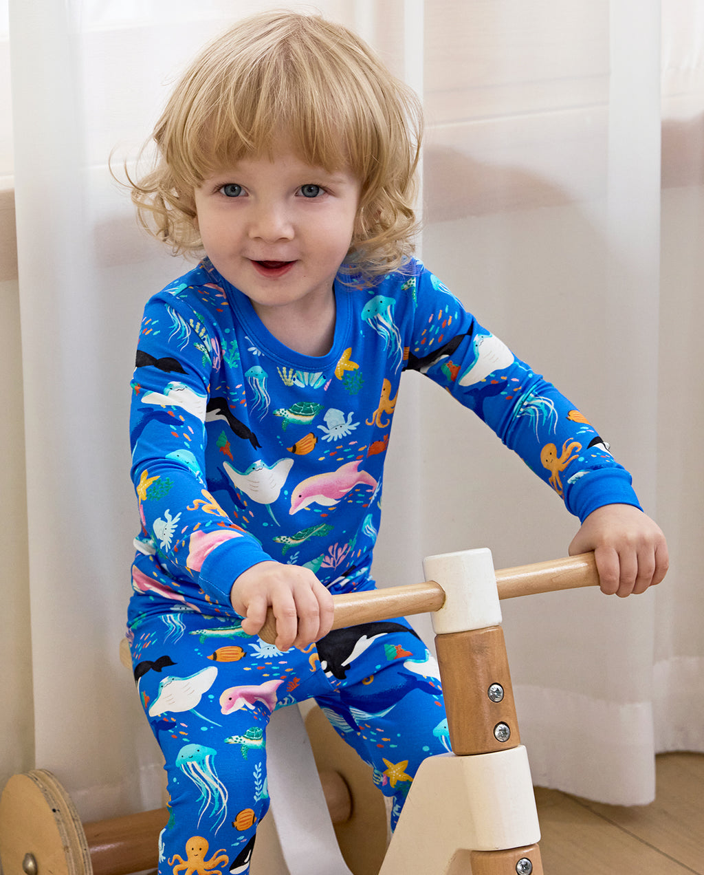 Child riding a wooden toy in blue sea-creature pajamas