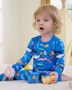 Child seated on a bed in blue Ocean Friends pajamas