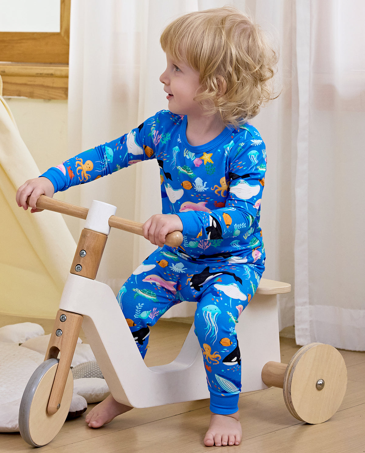 Side view of a child on a wooden toy in sea-creature pajamas