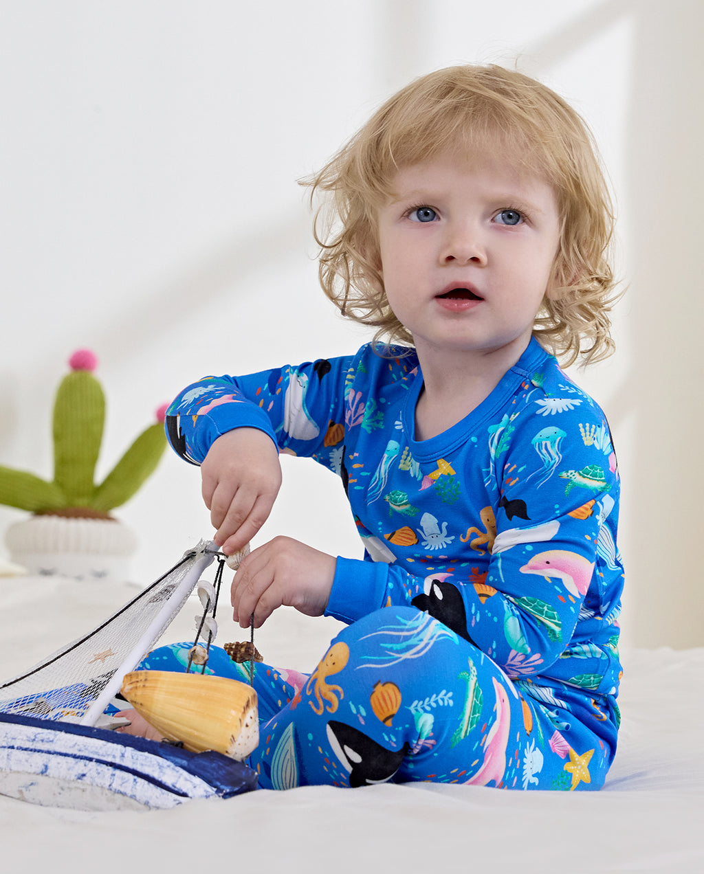 Child seated on a bed holding a basket in blue pajamas
