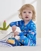 Child seated on a bed holding a basket in blue pajamas