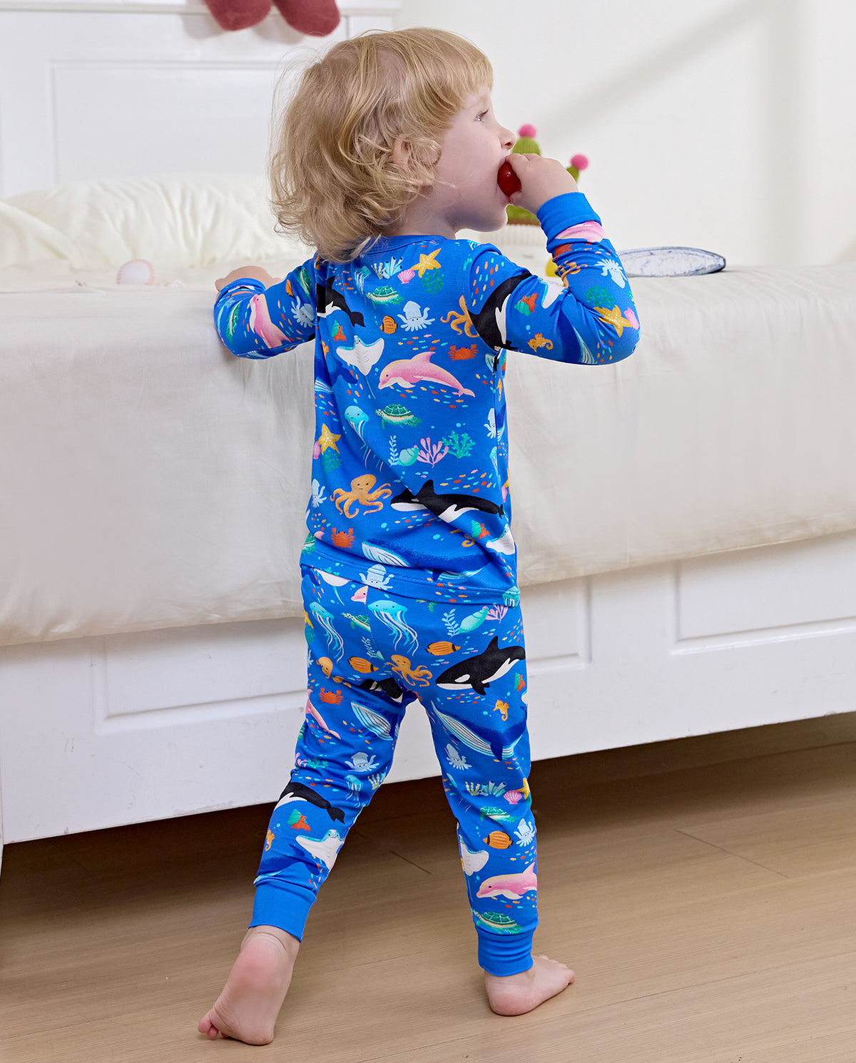 Child standing with a plush toy in blue Ocean Friends pajamas