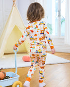 Back view of a child in Pumpkin Tractors long two-piece pajamas near a toy wagon.