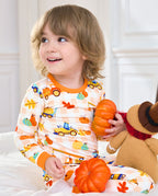 Child wearing Pumpkin Tractors long two-piece pajamas while holding a pumpkin and plush scarecrow.